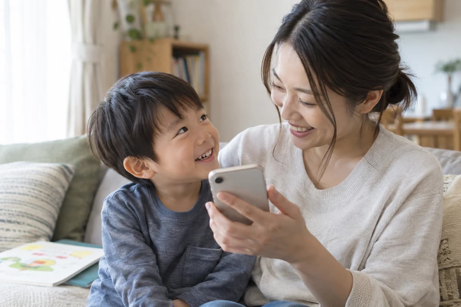 保護者と一緒にお友達の声を聴いて笑う子どものイメージ